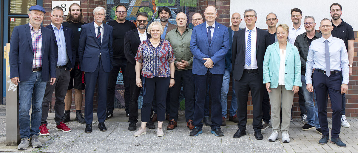 XIII Senat Die Personen stehen in einer Gruppe nebeneinander vor dem Eingang von Haus 18.