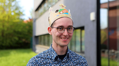 Der Science Slam-Siger ist mit einer Pappkrone auf dem Kopf im Porträt zu sehen.