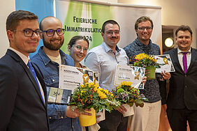 alle sechs PErsoenen stehen schräg hintereinander vor einem farbigen Banner auf dem steht: "Feierliche Immatrikulation 2024"