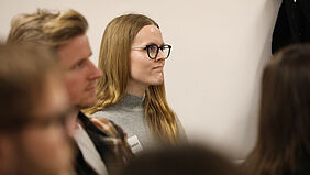 Ruth Kasdorf sitzend. Im Vordergrund sitzt ein Doktorand der Hochschule Wismar. Sie schauen beide einen Vortragenden des Kolloquiums an, der nicht im Bild zu sehen ist.