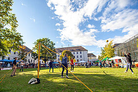 Es sind Studierende zu sehen, die Volleyball auf der Campuswiese spielen.