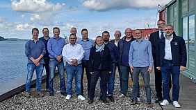 Die Gruppe steht auf der Dachterasse vor dem Konferenzraum des TZF. Über ihr ist ein wunderschöner Himmel mit Wolken zu sehen.