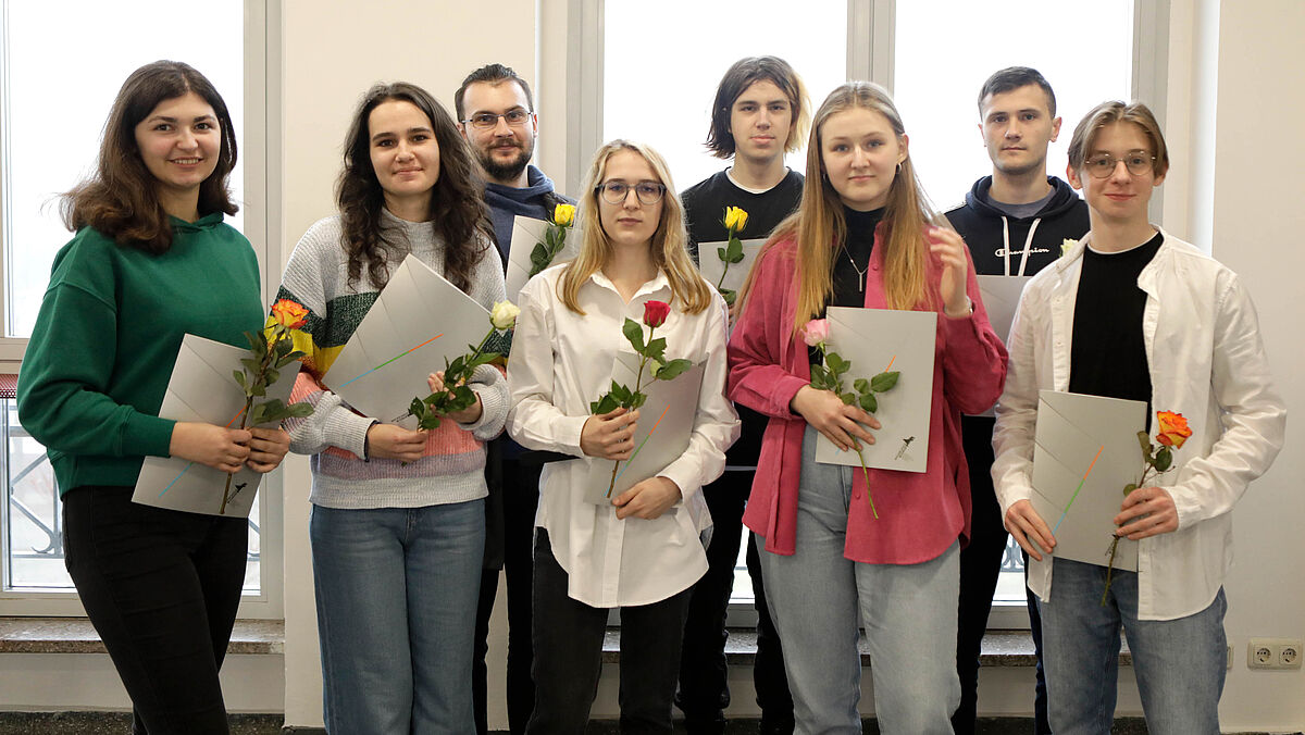 Es sind alle acht Stipendiaten zu sehen mit Urkunde und Blumen in der Hand.