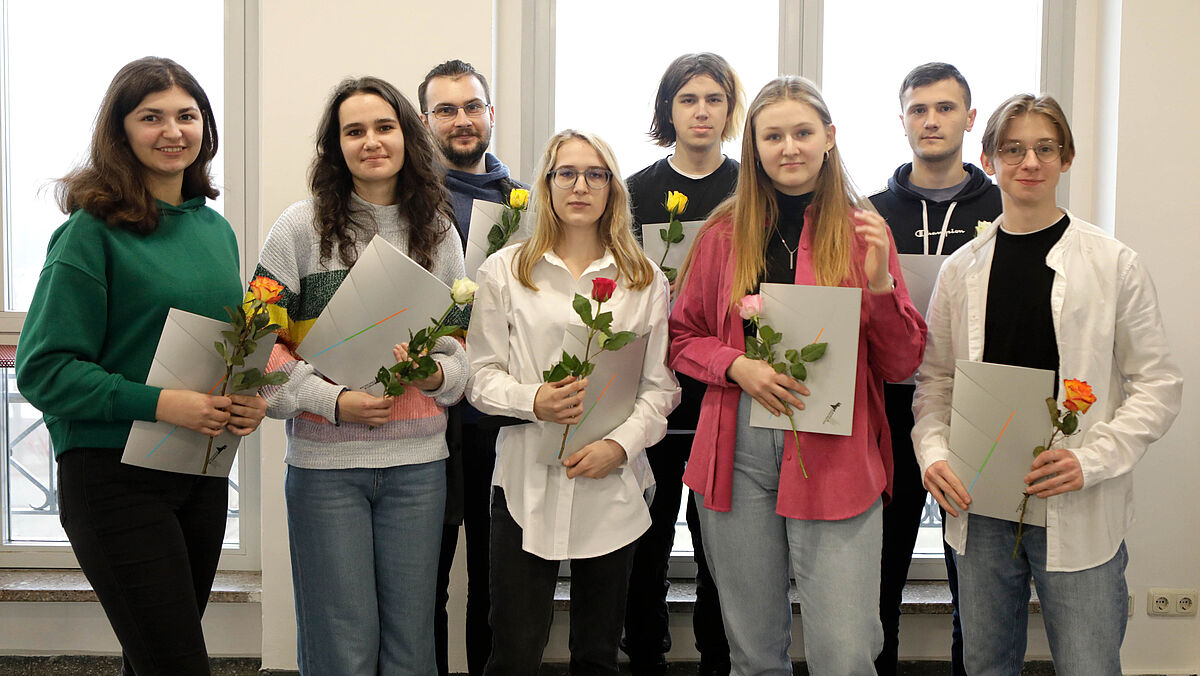 Es sind alle acht Stipendiaten zu sehen mit Urkunde und Blumen in der Hand.